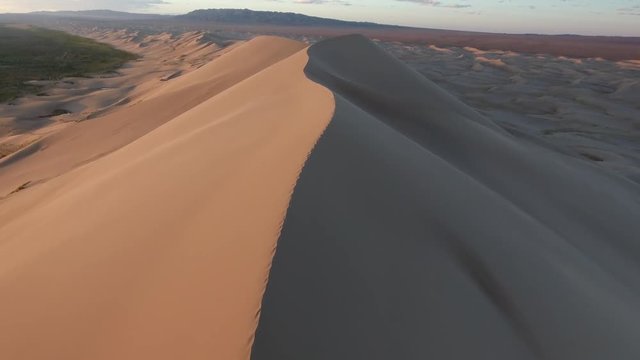 Aerial drone shot in gobi desert following the edge of a sand dune in Mongolia