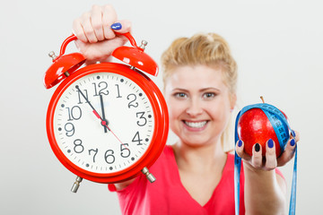 Happy woman holding clock, apple and measuring tape