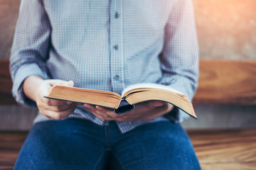 a man sit on wooden chair and reading bible or book over concrete wall with window light