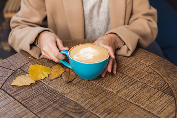 Girl's hands holding a hot cup of coffee close-up. Autumn