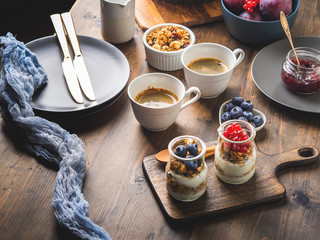Cozy Breakfast concept on dark wooden textured background. Coffee and yogurt with home made granola