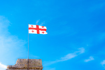Flag of Georgia on a background of blue cloudy sky