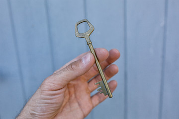 Old vintage brass door Key in mans hand