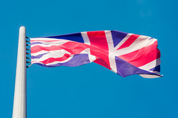 the flag of Great Britain flying in the wind against a blue sky