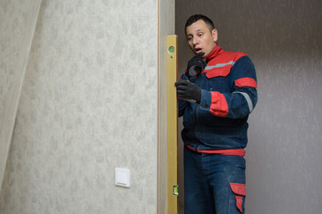 Male carpenter at interior wood installation and working with level measuring tape