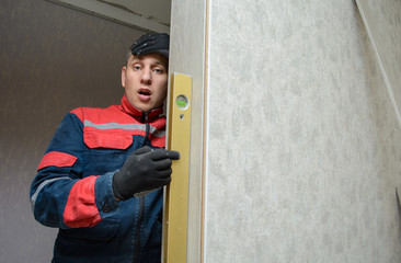 Male carpenter at interior wood installation and working with level measuring tape