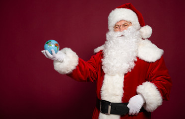 Santa Clause with earth globe on hand on red background, Christmas and New year concept