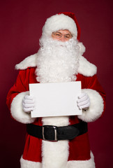 Happy grandfather Santa Clause showing white blank poster or board on red background, Christmas and New year concept