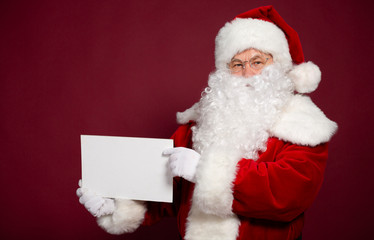 Happy grandfather Santa Clause showing white blank poster or board on red background, Christmas and New year concept