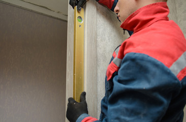 Male carpenter at interior wood installation and working with level measuring tape