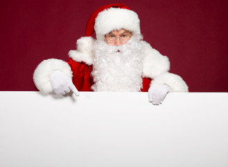 Santa Clause pointing at white blank banner on red background, Christmas and New year concept