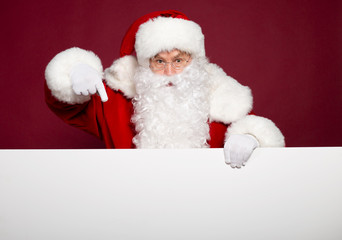 Santa Clause pointing at white blank banner on red background, Christmas and New year concept