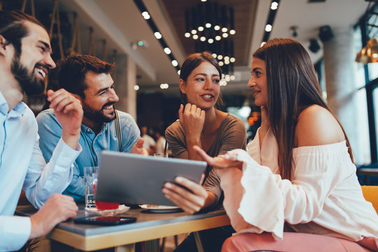 Group of Happy friends having with digital tablet in cafe