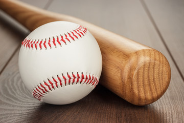 closeup of baseball bat and ball on wooden table