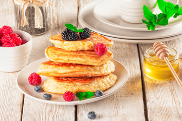 Delicious ready-made golden pancakes with fresh blueberries, raspberries and honey