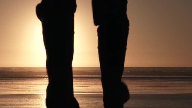 Man at the coast walking out to enjoy the sunset on sandy beach all to himself.