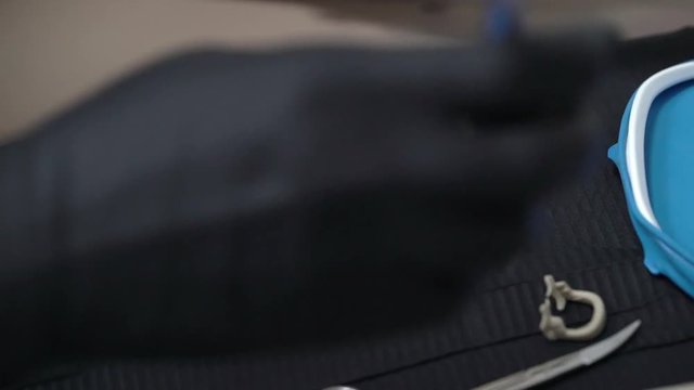 Tools for installing the cofferdam (rubberdam and clamp) lying on the table a black background in clinic