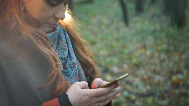 girl with stands in the forest in the autumn forest and writes sms