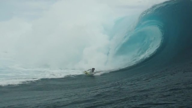 Man body surfing a perfect barrel in teahupoo french polynesia tahiti