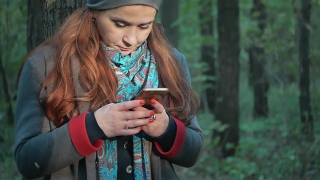 girl with stands in the forest in the autumn forest and writes sms