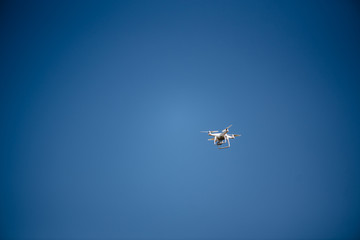 Flying drone of quad copter in clear blue sky