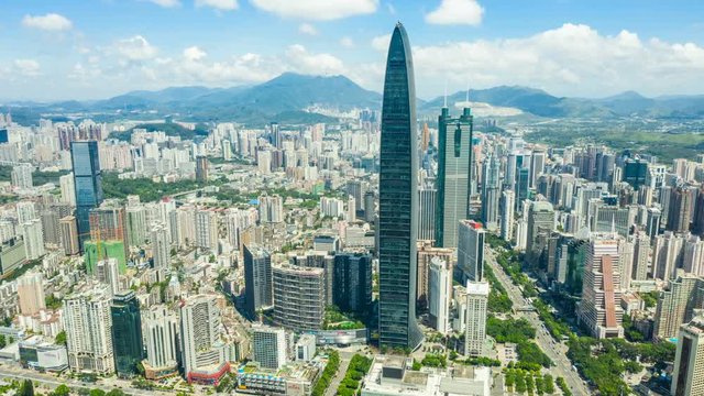 Aerial hyper lapse of Shenzhen cityscape under cloudy sky.