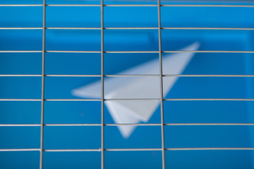 Russia is blocking Telegram: silhouette of a paper plane behind bars on a blue background