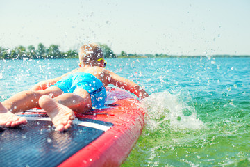 Boy swimming on stand up paddle board.Water sports , active lifestyle.	
