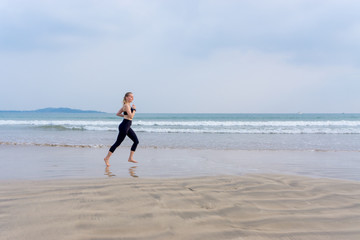 The girl runs along the Tropical beach doing sports