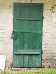 old metal and wood door with a rusty lock in a makeshift cellar dug in the ground