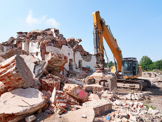 Excavator working in rubble. Old building ruins view.