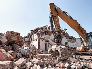 Old house demolition. Excavator working in rubble. Heavy machine