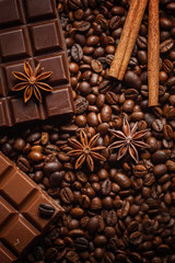 Texture spilling coffee beans, chocolate, cinnamon and cloves. Top view. Copy space.