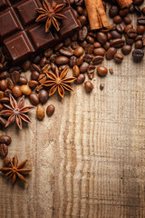 Obraz na płótnie Canvas Texture spilling coffee beans, chocolate, cinnamon and cloves. Top view. Copy space.