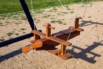 swing wooden plane hanging on ropes on the playground