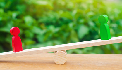 wooden figures of people. rivals in business stand on the scales. trial. conflict. victory and...