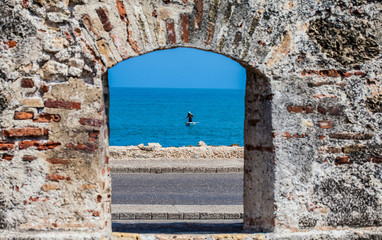 Fisherman on his boat seen through the embrasure of the city walls in the Cartagena de Indias