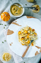 Pasta with pumpkin in a cream sauce in a craft bowl. Handmade ceramic plate. Autumn meal for lunch.