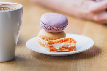 French colored macarons on the plate and a cup of coffee