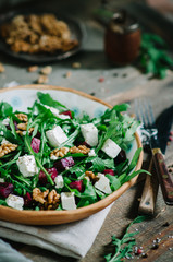 Salad with beets, walnuts, feta cheese and arugula. Rustic style salad on a dark wooden background