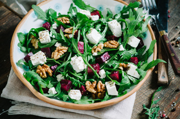Salad with beets, walnuts, feta cheese and arugula. Rustic style salad on a dark wooden background