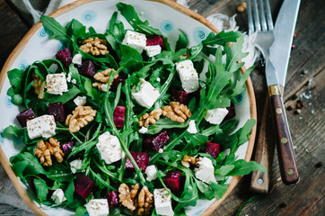 Salad with beets, walnuts, feta cheese and arugula. Rustic style salad on a dark wooden background
