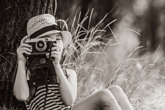 photo of the beautiful girl taking photos with her camera near the tree . Image in black and white color style
