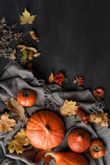 Autumn composition with dry leaves and ripe pumpkins on a dark wooden table. Top view. Copy space