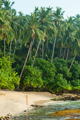 Girl in swimsuit walks on a tropical beach