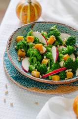 Salad with baked pumpkin, apple, broccoli and pine nuts. Ceramic plates handmade. Rustic style.