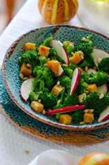 Salad with baked pumpkin, apple, broccoli and pine nuts. Ceramic plates handmade. Rustic style.