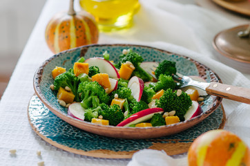 Salad with baked pumpkin, apple, broccoli and pine nuts. Ceramic plates handmade. Rustic style.