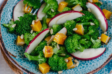 Salad with baked pumpkin, apple, broccoli and pine nuts. Ceramic plates handmade. Rustic style.