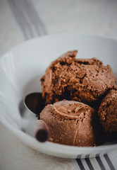 Homemade chocolate ice cream in a bowl with a spoon. Low view shot, close up.